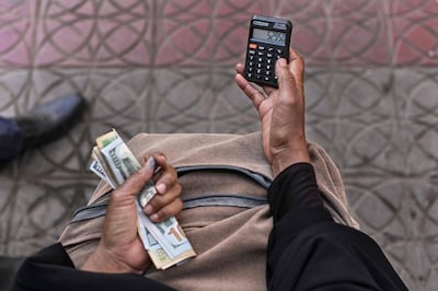 Noura Hassan, uses a pocket calculator to convert the worth of US dollars offered by a client into Djiboutian francs at a street corner where she sits cradling a satchel filled with a variety of regional and international currencies, waiting on customers to come by for foreign-exchange (Forex) services in Djibouti's capital on April 11, 2021.  When her husband died a decade ago, the mother-of-three started out with just her savings in francs, before acquiring more currencies.
Every day, Hassan refers to a printout from the local bank to gauge exchange rates and determines what to offer customers for the major currencies. / AFP / TONY KARUMBA
