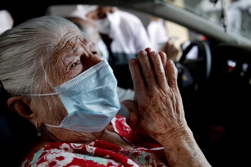 A woman thanks god after being vaccinated against covid-19 at a drive-in center in Sao Paulo, Brazil. A drive-in center to vaccinate elders against covid-19 went into operation at the Pacaembu stadium in Sao Paulo, as part of a health program against the pandemic.  EPA