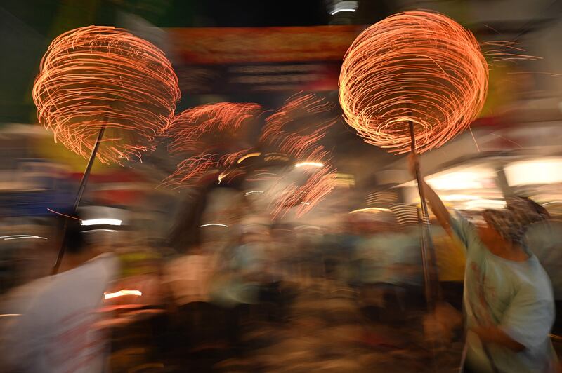 Members of the fire dragon dance team spin balls of joss sticks, as the 'dragon' winds through the narrow streets and houses, during the Tai Hang Fire Dragon Dance in Hong Kong. AFP