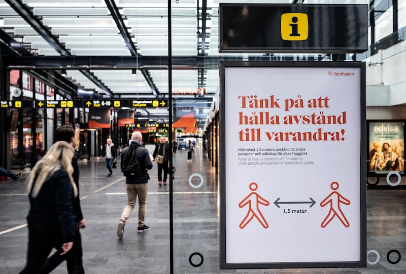 People pass a sign reading 'Remember to keep distance from each other' at Malmoe C train station in Malmoe, Sweden. EPA