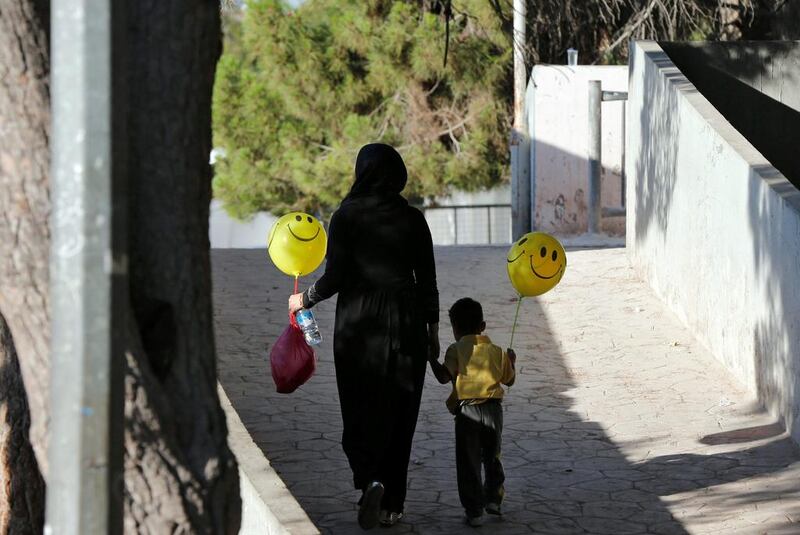 A woman and a child carry balloons after Eid Al Fitr prayers in Amman. Reuters