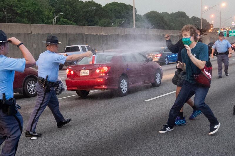 An officer attacks a protester with pepper spray after a group went on the interstate motorway after leaving the protest site near the Wendy's restaurant, which was destroyed in Atlanta, Georgia.  EPA
