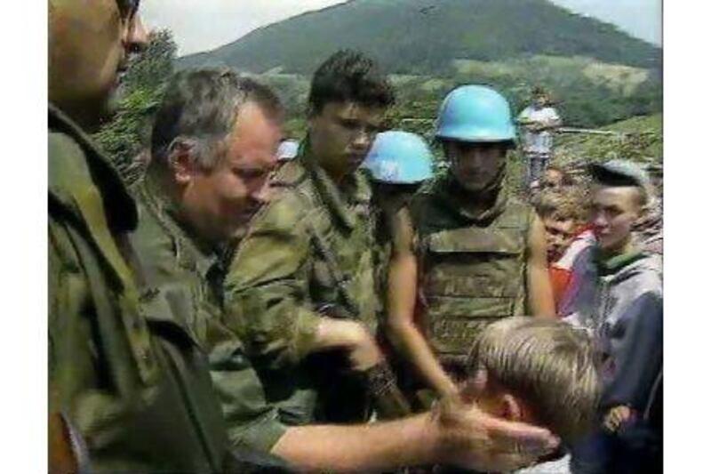 Bosnian Muslim boy Izudin Alic being patted on the head by a grinning Ratko Mladic in 1995, who assured him that everyone in Srebrenica, Bosnia, would be safe. AP Photo