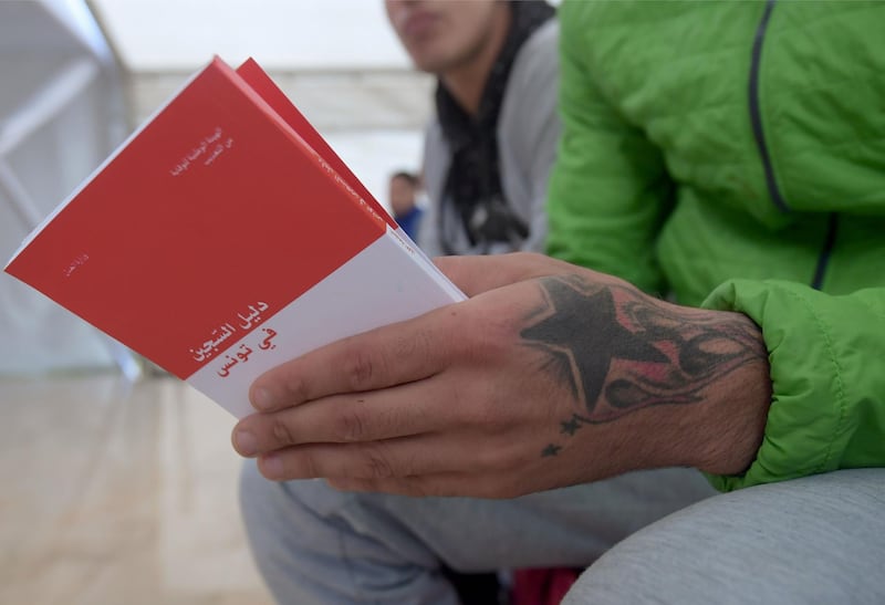 A prisoner holds booklets distributed by Tunisian officials and intended for all inmates and prison guards in Tunisia, that inform them about human rights in a simplified manner, in Mornaguia prison near the capital Tunis.  AFP