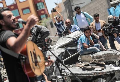 A Palestinian singer Rami Okasha performs during a musical party calling to boycott the Eurovision Song Contest hosted by Israel, on the rubble of a building that was recently destroyed by Israeli air strikes, in Gaza City. Photo by Majd Mahmoud 