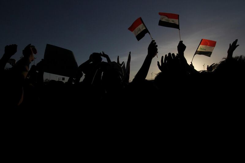 Iraqi protesters wave national flags in front of the provincial council building during a demonstration demanding better public services and jobs, in Najaf, 100 miles (160 kilometers) south of Baghdad, Iraq, Friday, July 20, 2018.  Some thousands have once again taken to the streets in the capital and the southern city of Basra demanding better public services and jobs. (AP Photo/Anmar Khalil)