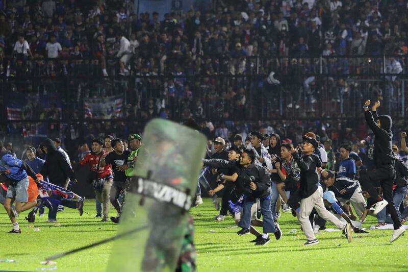 Football fans enter the pitch during a clash between supporters at Kanjuruhan Stadium.  Clashes between supporters of the two teams killed 129 fans and a number of police officers, mostly trampled to death, police said Sunday. AP