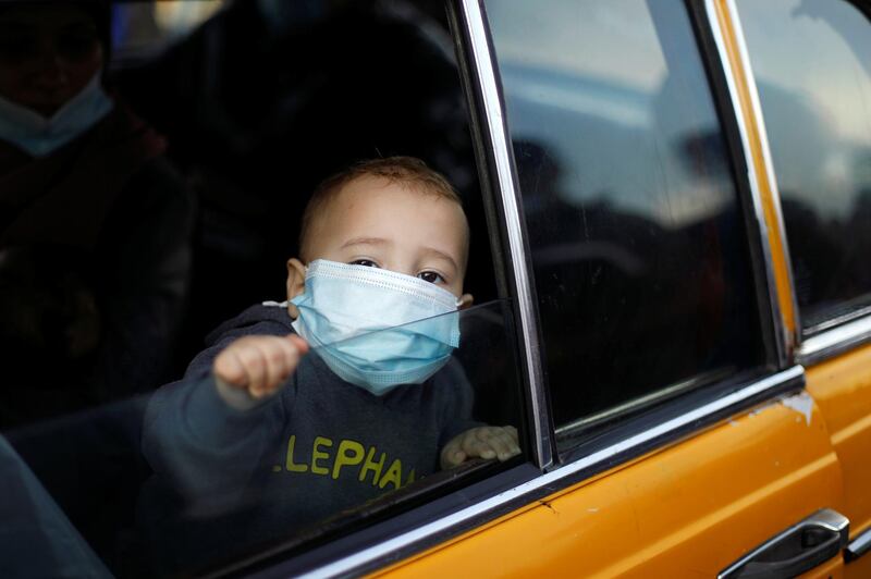 A boy wearing a protective face mask looks out of a car as he waits to leave the Palestinian Rafah border crossing with Egypt, which was reopened partially amid the spread of the coronavirus disease (COVID-19), in the southern Gaza Strip. REUTERS