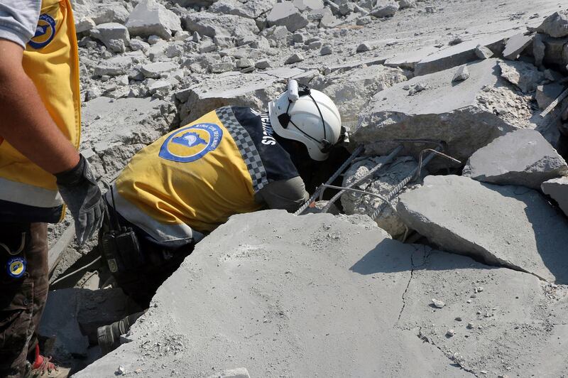 This photo provided by the Syrian Civil Defense White Helmets, which has been authenticated based on its contents and other AP reporting, shows a Civil Defense worker searching for victims from under the rubble of a destroyed building that hit by airstrikes, in Deir al-Sharqi village, in Idlib province, Syria, Saturday, Aug 17, 2019. Syrian activists and a war monitor say airstrikes have pounded the southern edge of a rebel stronghold in the country's northwest, in one instance killing seven including children. (Syrian Civil Defense White Helmets via AP)