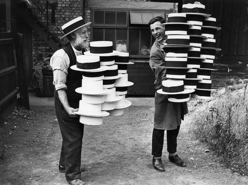 Workers at a hat manufacturers in Luton, in 1928, carrying piles of men's straw hats, which were in demand due to a heatwave.