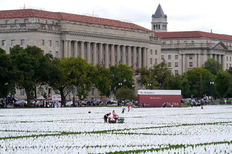 People visit artist Suzanne Brennan Firstenberg's "In America: Remember," a temporary art installation made up of white flags to commemorate Americans who have died of COVID-19, on the National Mall in Washington, Tuesday, Sept.  21, 2021.  (AP Photo / Patrick Semansky)