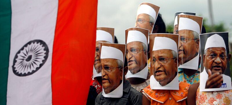 Supporters of veteran Indian social activist Anna Hazare wearing portraits of Hazare attend a protest against corruption next to the Indian national flag in Agartala, capital of India's northeastern state of Tripura, August 18, 2011. India's beleaguered government caved in to popular fury over corruption on Wednesday after thousands protested across the country, granting permission for a self-styled Gandhian crusader to stage a 15-day hunger strike in public. Hazare was arrested on Tuesday, hours ahead of a planned fast to demand tougher laws against the graft that plagues Indian society from top to bottom. REUTERS/Jayanta Dey (INDIA - Tags: POLITICS CIVIL UNREST) *** Local Caption ***  DEL12_INDIA-PROTEST_0818_11.JPG