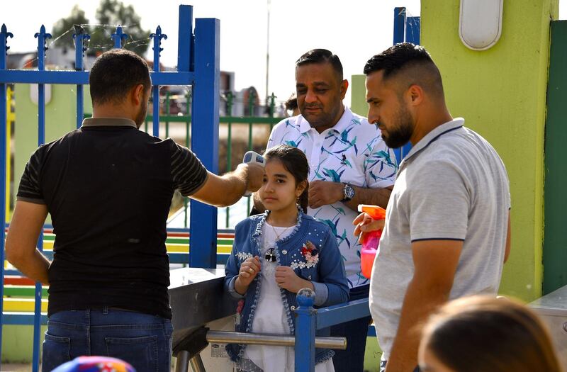 An Iraqi measures the temperature of families entering a park in Mosul during Eid Al Fitr.  AFP