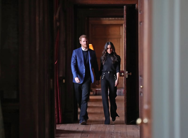 Prince Harry and Meghan walk through the corridors of the Palace of Holyroodhouse on their way to a reception for young people at the Palace in February 2018 in Edinburgh, Scotland. Getty