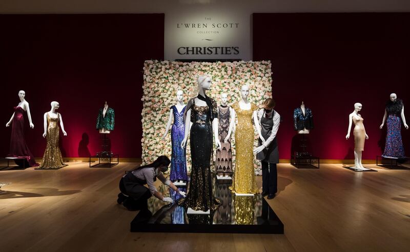 A member of staff handles a black and gold sequined 'Oscar' dress (L) worm by Nicole Kidman and a gold sequined gown (R) worn by Penelope Cruz at the L'Wren Scott Collection photocall at Christie's Auction House in London.  EPA/Vickie Flores