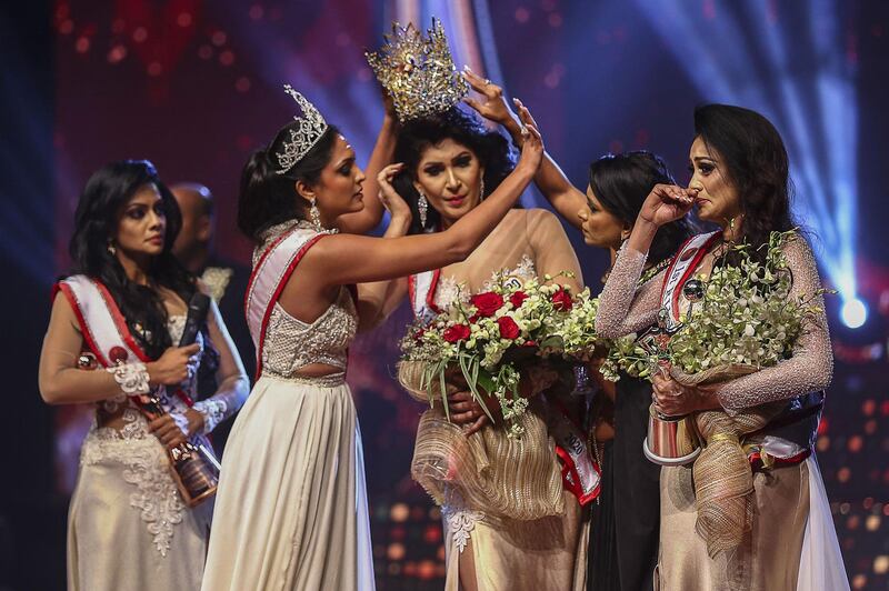 Former Mrs World Caroline Jurie, left, removes the crown of 2021 winner Pushpika de Silva, centre, as she attempts to disqualify her over the accusation of being divorced, at a beauty pageant for married women in Colombo. AFP