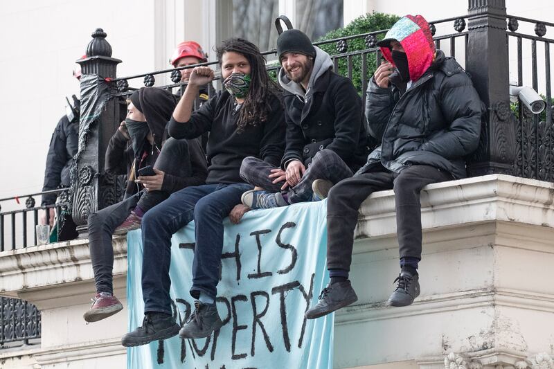People sitting on the balcony of a west London mansion belonging to Russian oligarch Oleg Deripaska, with a banner reading, 'This property has been liberated'. EPA