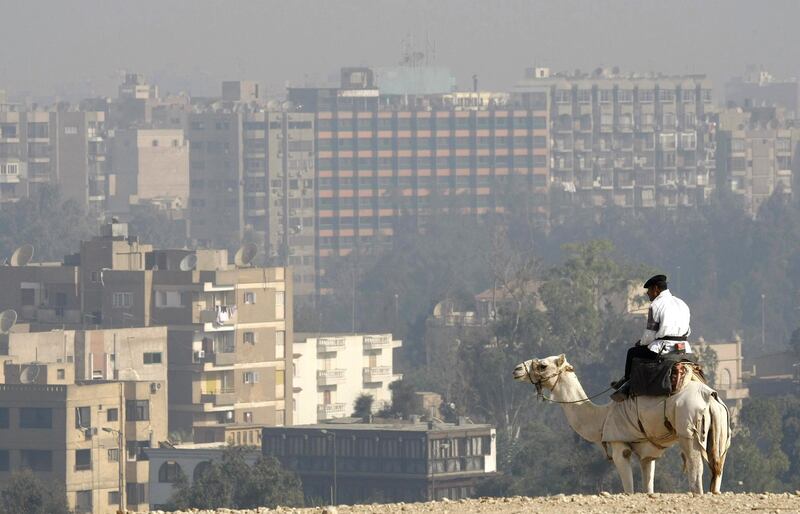 A camel-mounted tourism policeman in the Giza Plateau silhouettes against the pollution smog covering the city of Cairo 23 October 2007. For the eighth consecutive year, pollution is causing serious respiratory infections in the city with a population of over 17 million, with levels of NO2 measuring 305-482 mg in Giza and Cairo, double the threshold set by the World Health Organisation (WHO). The pollution is attributed to the seasonal burning of rice straws to mark the end of the holy month of Ramadan, the daily open-air incineration of 12,000 tons of domestic refuse, in addition to the emission of polluting substances from industries and more than 1.6 million vehicles in Cairo and adjacent neighbourhoods. AFP PHOTO/CRIS BOURONCLE (Photo by CRIS BOURONCLE / AFP)
