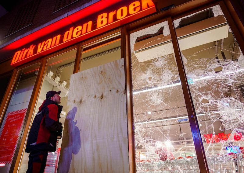 A worker boards up broken windows on a branch of supermarket chain Dirk van den Broek in Rotterdam. AFP