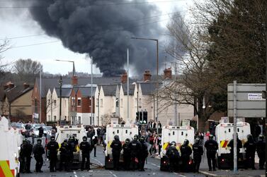 Police form a line to stop Nationalists and Loyalists attacking each other, as a hijacked bus burns in the distance in Belfast, Northern Ireland, April 7. AP