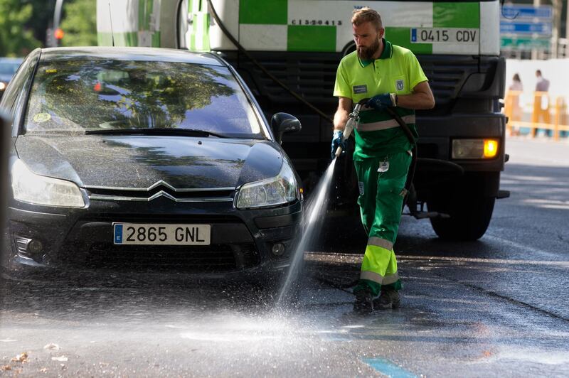 A municipal worker hoses down a street in Madrid, Spain.  AP