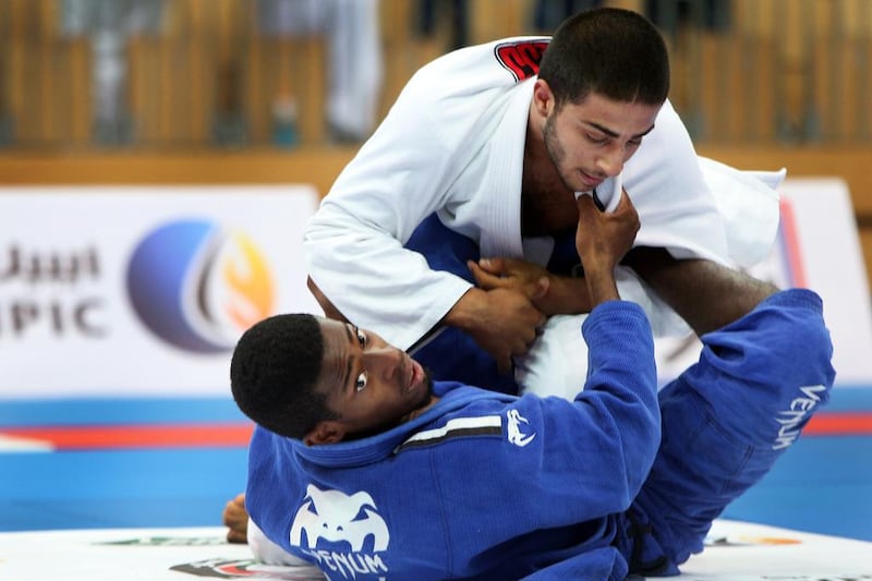 Abdullah Aljneibi, bottom, of the Al Jazira Jiu-Jitsu club, checks the remaining time while keeping a tight hold on his opponent from UAE JJF Training Center, during their match in the first leg of the inaugural President's Cup, an open competition for clubs. The event was held at the Ipic Arena at Zayed Sports City in Abu Dhabi on Saturday, August 27, 2016. Aljneibi won the match. Delores Johnson / The National