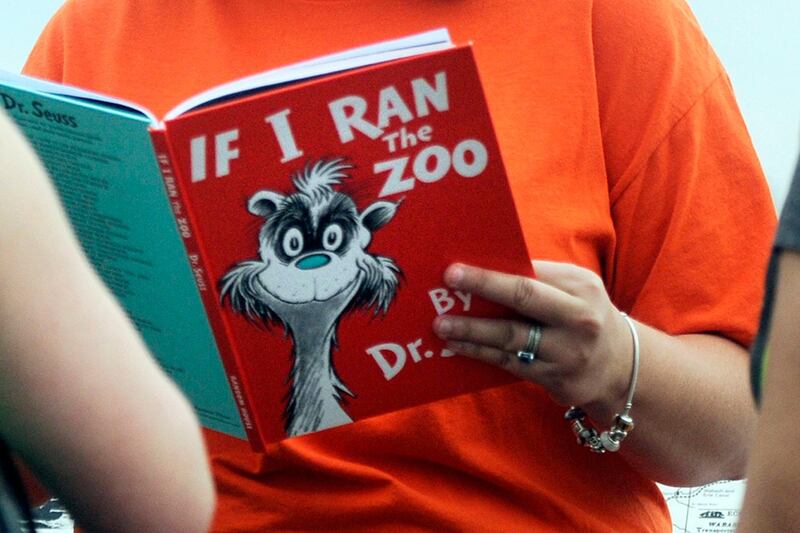 FILE - In this Sept. 24, 2013, file photo, Courtney Keating, education coordinator of The Literacy Center in Evansville, Ind., reads "If I Ran the Zoo," By Dr. Seuss, to passersby during an event to promote literacy along the Evansville Riverfront. Dr. Seuss Enterprises, the business that preserves and protects the author and illustrator's legacy, announced on his birthday, Tuesday, March 2, 2021, that it would cease publication of several children's titles including "And to Think That I Saw It on Mulberry Street" and "If I Ran the Zoo," because of insensitive and racist imagery. (Erin McCracken/Evansville Courier & Press via AP, File)