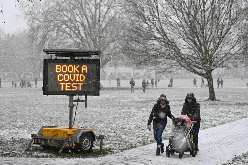 A sign advising people to get a covid-19 test is displayed in a park as snow falls in west London, as the capital experiences a rare covering of snow on Sunday. AFP