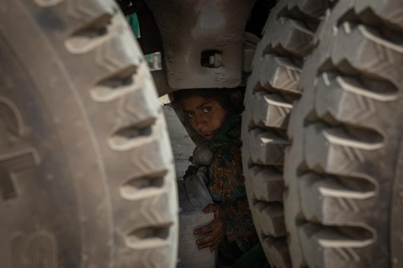 A young girl from Afghanistan hides under a truck carrying fruit and vegetables as she attempts to smuggle herself over the border from Afghanistan into Pakistan on September 12, 2021. Everyday dozens of children from Afghanistan smuggle themselves over the border into Pakistan to sell Paan and other goods before smuggling themselves back again. At least one child is injured each day trying to cross the border like this. Oliver Marsden for The National