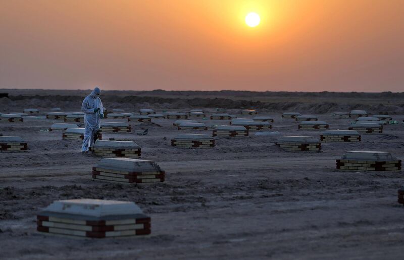 An Iraqi man in a hazmat suit takes pictures of a relative's tombstone at a cemetery for COVID-19 victims, 20 km from the central Iraqi holy city of Najaf, on June 10, 2020. (Photo by Ali NAJAFI / AFP)