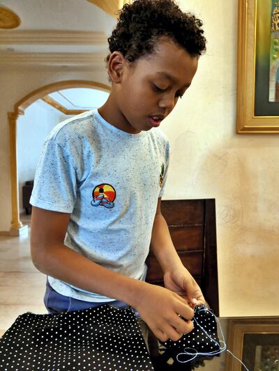 Pictured: Mogtaba Khalifa, 10, stiches together fabric to make a face mask. He has no prior experience of sewing before starting the project so it has been a big learning curve but his mother and people within the community in Amman, Jordan, are offering their support. 
2020-14-06
Picture by Charlie Faulkner