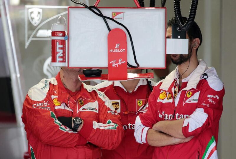 Members of Scuderia Ferrari look at a monitor inside the team garage during qualifying for the Japanese Formula One Grand Prix at the Suzuka Circuit in Suzuka, central Japan. Yuya Shino / EPA