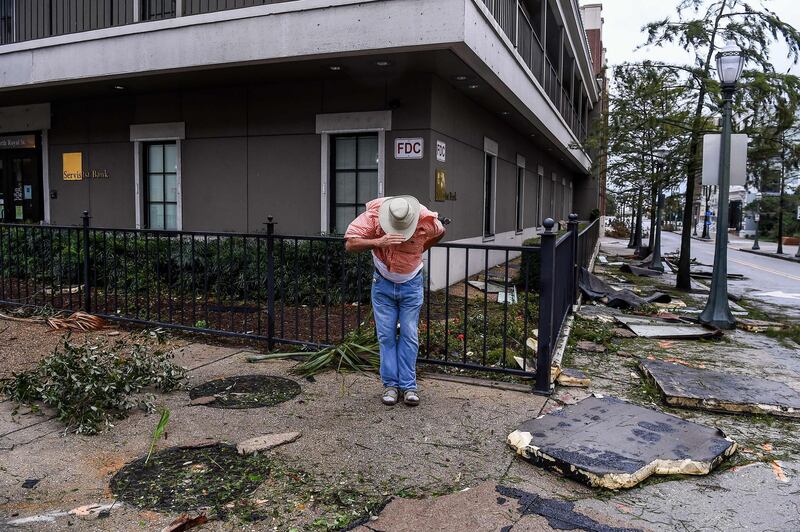 A man saves his hat in the strong wind during Hurricane Sally landfall in Mobile, Alabama. AFP