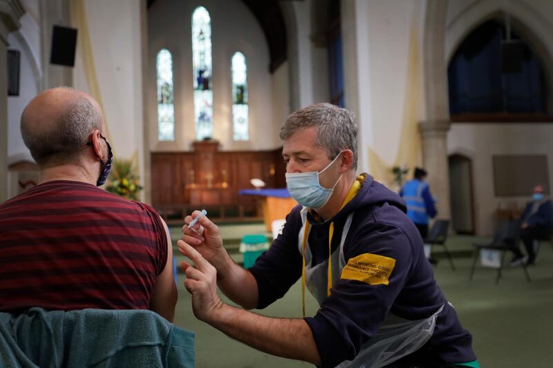 Nick Gray, a St Johns Ambulance vaccinator gives the AstraZeneca vaccine at St John's Church, in Ealing, London. AP Photo