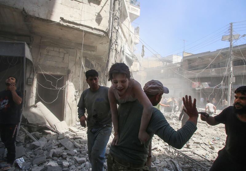 A man evacuates a young bombing casualty after a reported air strike by regime forces and their allies in Maaret Al-Noman in the southern Idlib province, on May 26, 2019.  AFP