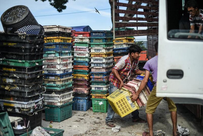 Workers carry empty fruits boxes to a lorry at a wholesale market in Kuala Lumpur, Malaysia, on September 23, 2016. / AFP / MOHD RASFAN