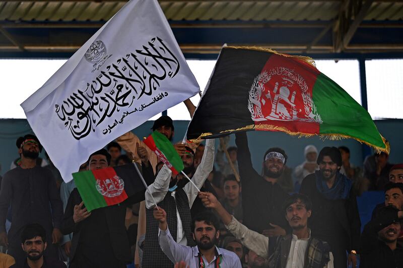 Spectators wave Afghanistan's and Taliban flags as they watch a Twenty20 cricket trial match at the Kabul International Cricket Stadium in Kabul on September 3, 2021. AFP