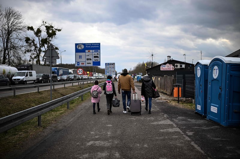 Ukrainian refugees Julia, second left, 32, and Miroslava, left, 11, walk away with relatives who received them after they crossed into Poland from Ukraine at the Dorohusk border. AFP