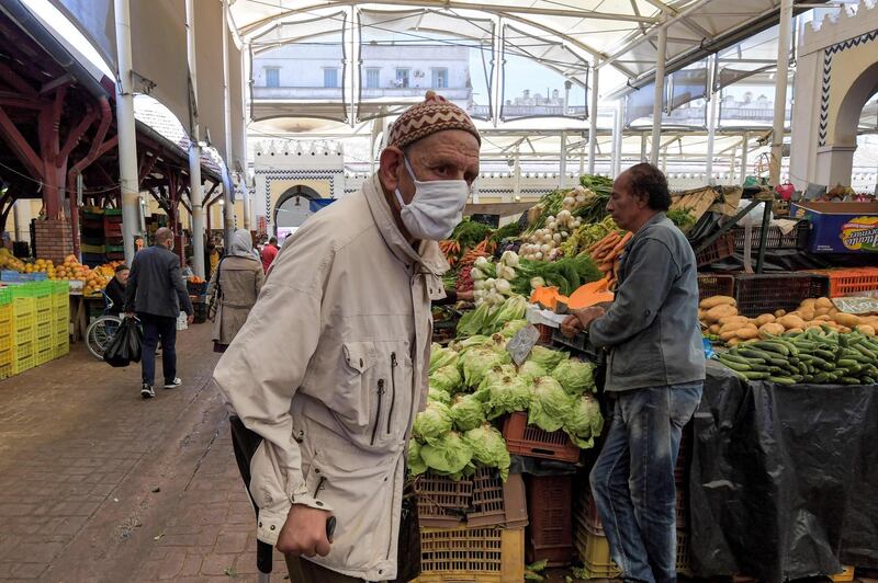 An elderly man wearing a face mask due to the COVID-19 coronavirus pandemic walks with a crutch at the central market in the Tunisian capital Tunis on May 4, 2020, as Tunisian authorities begin a gradual sector and region-based deconfinement process. To find a balance between socio-economic needs and the preservation of health, the Tunisian government established a system in three stages, hoping to fully restart the country by June 14. / AFP / FETHI BELAID
