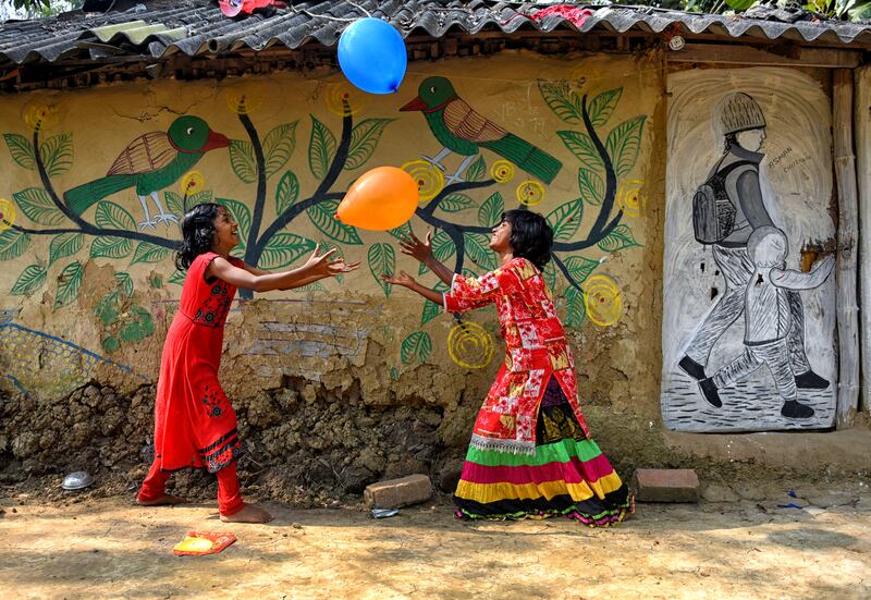 Village children play with balloons beside a decorated wall in Naya village in West Bengal, India, which is famous for ancient folk art. Getty Images