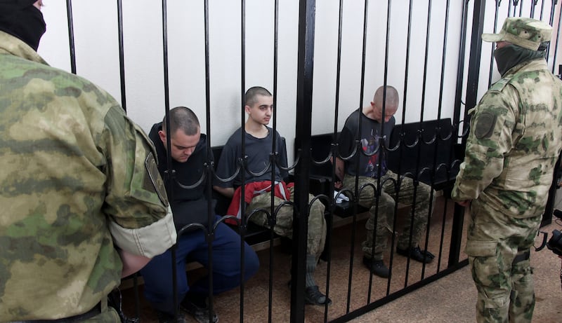 British citizens Aiden Aslin, left, and Shaun Pinner, right, and Moroccan Saaudun Brahim, centre, sit behind bars in a courtroom in the breakaway eastern Ukrainian enclave of Donetsk. The three were sentenced to death by pro-Moscow rebels for fighting on Ukraine's side. AP