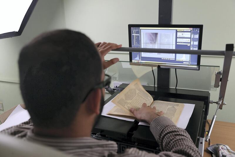 DUBAI , UNITED ARAB EMIRATES , FEB 20  – 2018 :- Worker scanning the book into digital format at the Juma Al Majid Centre for Culture and Heritage in Dubai. ( Pawan Singh / The National ) For Arts & Life. Story by Melissa Gronlund