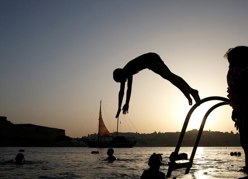 A boy dives into the sea as a Turkish gulet serving as a floating stage during the Malta International Arts Festival sails by, in Rinella Bay in the village of Kalkara, in Valletta's Grand Harbour, Malta, July 8, 2019.  REUTERS/Darrin Zammit Lupi