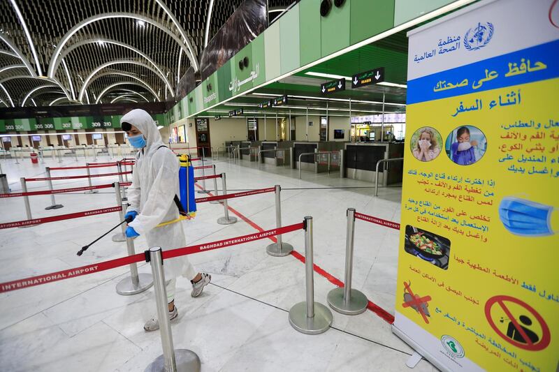 A worker wearing a protective suit sprays interiors departure hall of Baghdad International Airport. REUTERS