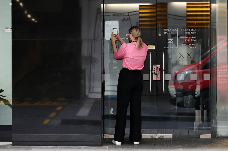 A woman reads a sign in the window of the A-Z Collection store on High St in Auckland, New Zealand. Getty Images