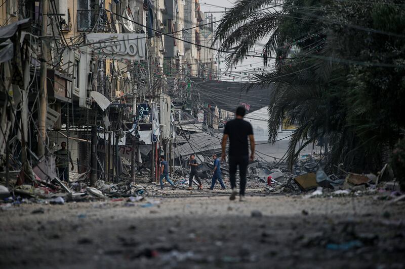Palestinians walk amid the rubble following an Israeli air strike in Al Sheikh Redwan neighbourhood in northern Gaza city. EPA