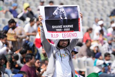 A cricket fan holds a placard to pay tribute to the Australian cricketer Shane Warne on the third day of the first test match between India and Sri Lanka in Mohali, India, Sunday, March 6, 2022.  (AP Photo / Altaf Qadri)
