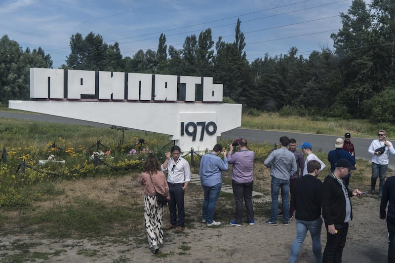 Tourists stop for pictures at a sign marking the entrance to the abandoned city of Pripyat. Getty Images