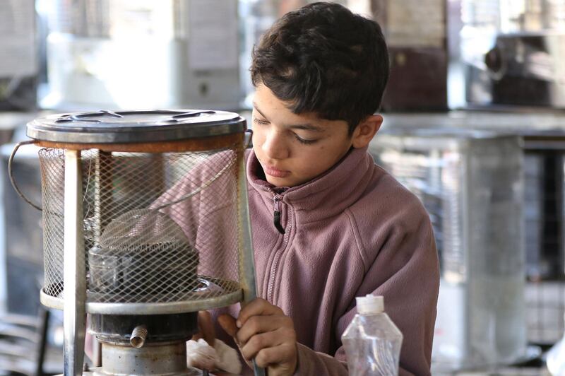 Omar, 14, fixes a kerosene heater in a workshop in Amman, where he works 12 hours a day. AFP