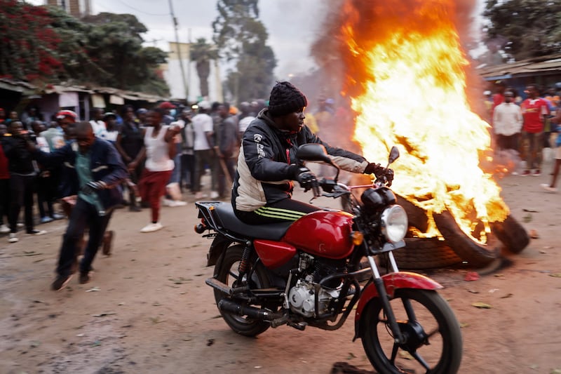 A man rides his motorcycle past supporters of Kenya's Azimio La Umoja Party presidential candidate Raila Odinga burning tyres in Kibera. There have been reports that the opposition could challenge the result. AFP